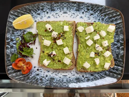 Smashed avocado and crumbled feta on two slices of toasted sourdough, with chilli flakes, lemon and a small salad.