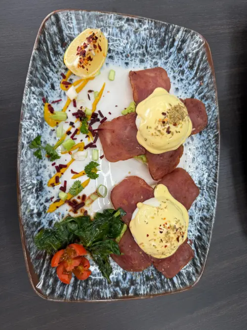 Two poached eggs under hollandaise with turkey rashers and sautéed spinach, dressed with saffron oil and dried barberries.