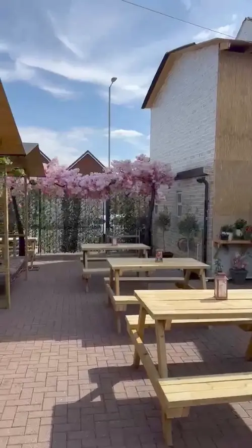The garden looking across the picnic tables towards the blossom tree and the cabanas, lanterns on the tables.